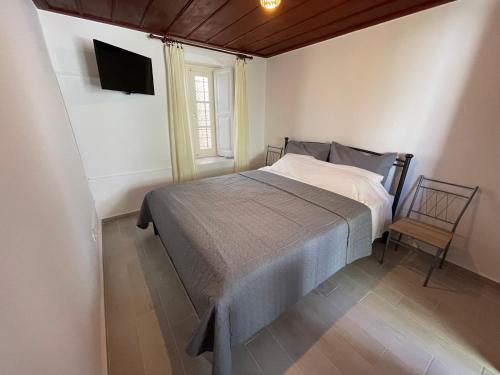 a bedroom with a bed and a chair and a television at Lemon House in Hydra