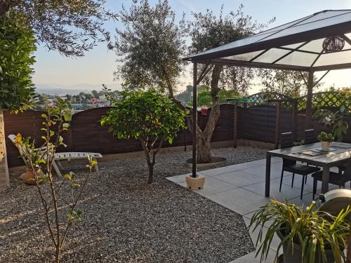 une terrasse avec une table, un parasol et des arbres dans l'établissement Charmant 2p au calme, jardin, piscine, vue panoramique et stationnement, à Villeneuve-Loubet