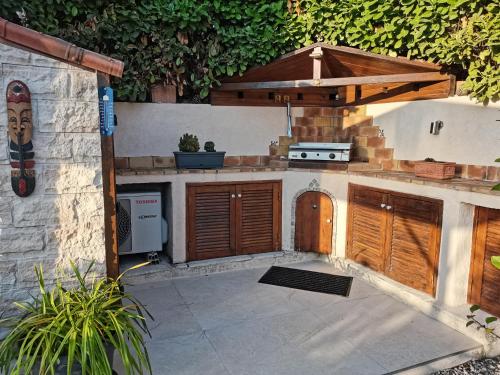 une cuisine extérieure avec des portes en bois et un grill dans l'établissement Charmant 2p au calme, jardin, piscine, vue panoramique et stationnement, à Villeneuve-Loubet