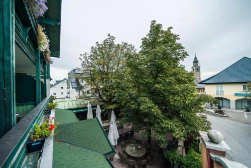 an apartment balcony with a tree on a city street at Hotel Berg in Seekirchen am Wallersee