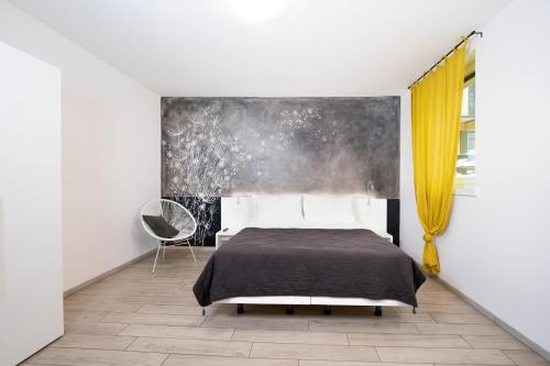 a bedroom with a bed and a yellow curtain at CityU Grazioli 27 Appartamento Trento Città - 2 stanze con 2 parcheggi privati gratuiti in Trento