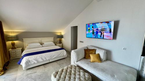 a bedroom with a bed and a couch and a tv at BANUS HAUSE Marbella in Marbella