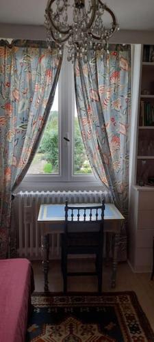 une chambre avec une table devant une fenêtre dans l'établissement Les Abélias, à Hauterive