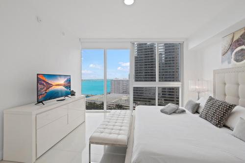 a white bedroom with a bed and a large window at 2B2B w Water View - FREE Parking - Pool - Lux Spa in Miami