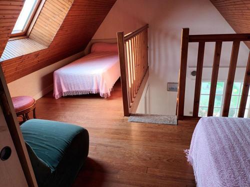 Cette chambre mansardée comprend deux lits et un escalier. dans l'établissement villa les pieds dans l'eau, à Plouhinec