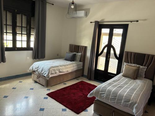 1 dormitorio con 2 camas y alfombra roja en Dar el kebira en Meknès