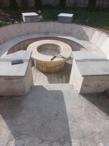 a stone patio with two benches and a fire pit at Nika Hangstigoti in Ptykhni