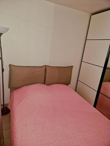 une chambre avec un lit avec une couverture rose dans l'établissement T2 rez de jardins, à Cavalaire-sur-Mer
