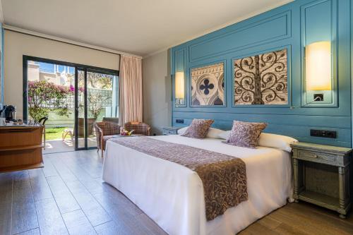 1 dormitorio con 1 cama grande y pared azul en Adrián Hoteles Colón Guanahaní Adultos Only, en Adeje