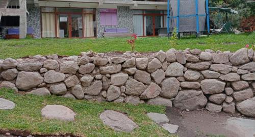 a stone retaining wall in front of a house at Illawasi Lofts in Urubamba