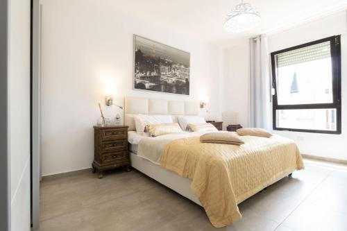 a white bedroom with a large bed and a window at King David Apartment - J&J in Jerusalem