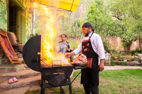 un homme dans un tablier qui cuisine de la viande sur un grill dans l'établissement Illawasi Lofts, à Urubamba