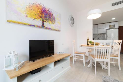 a living room with a tv and a dining room table at King David Apartment - J&J in Jerusalem