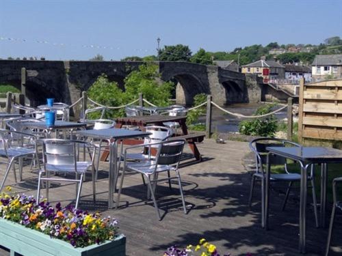 a patio with tables and chairs and a bridge at Anchor Hotel in Haydon Bridge