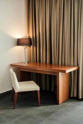 a desk with a lamp and a chair next to a curtain at Avala Resort & Villas in Budva