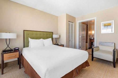 - une chambre avec un grand lit blanc et une chaise dans l'établissement Hilton Vacation ocean beach club Virginia Beach, à Virginia Beach