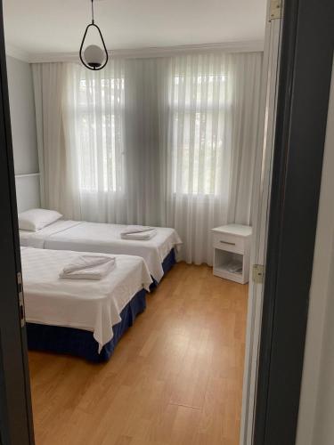 two beds in a small room with white curtains at İZAN VİLLA BAKIŞ APARTMENTS in Bodrum City