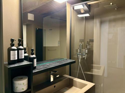 een badkamer met een wastafel met flessen op een spiegel bij Saragozza Suite 7 Attico con altana a due passi da Piazza Grande WIFI e parcheggio gratuito in Modena