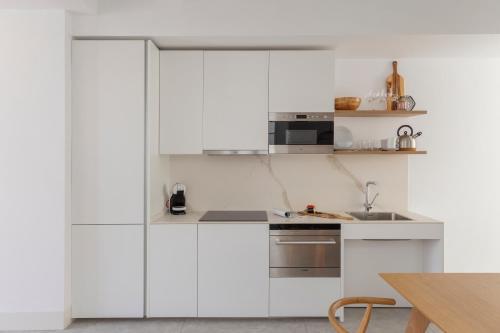 a white kitchen with white cabinets and a table at Candelaria10 in Cádiz