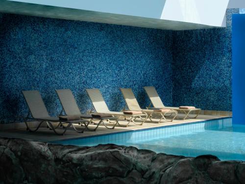 a row of chairs sitting next to a swimming pool at Atlantica Panthea Resort in Ayia Napa