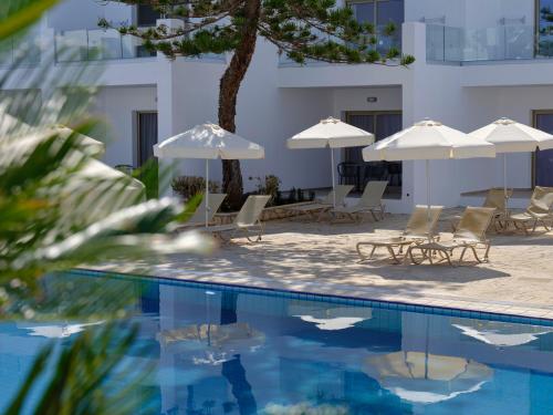 a swimming pool with umbrellas and chairs and a building at Atlantica Panthea Resort in Ayia Napa