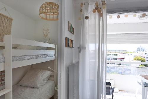 - une chambre avec des lits superposés blancs et un balcon dans l'établissement Studio le cocon, à La Grande Motte