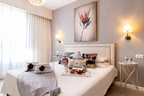 a bedroom with a white bed with flowers on it at King David Apartment - J&J in Jerusalem
