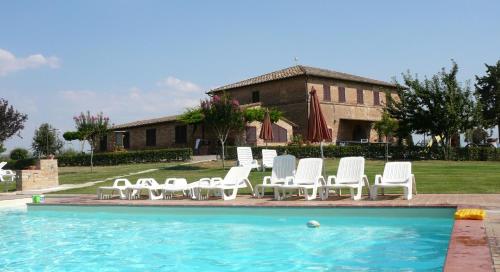 a group of white chairs sitting next to a pool at San Lorenzo Agriturismo in Buonconvento