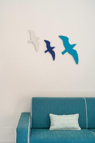 three birds on the wall above a blue couch at Casa Levante Luxury Apartments Capri in Capri