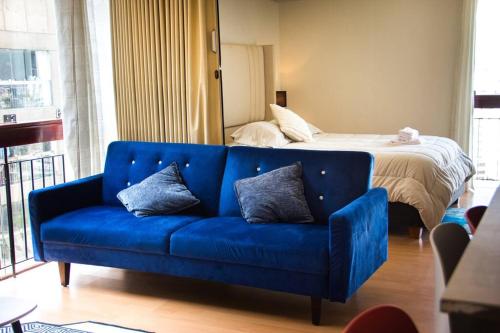a blue couch in a room with a bed at Departamento con vista de Lima en San Borja in Lima