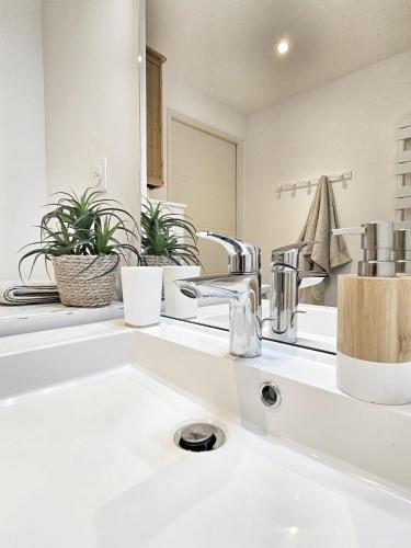 une salle de bain blanche avec un lavabo et un miroir dans l'établissement T2 design proche gare/Intra-M/Sillon, garage privé, à Saint-Malo