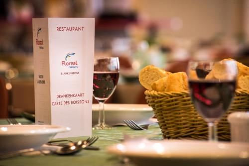 a table with two glasses of wine and a basket of bread at Floreal Blankenberge in Blankenberge