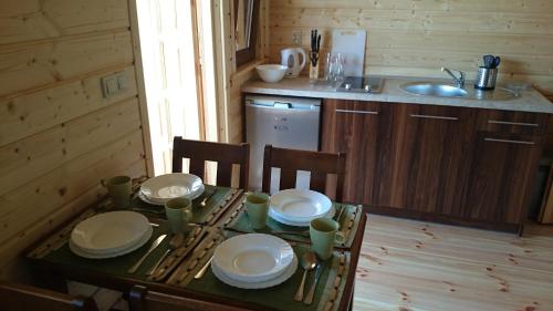 una cocina con una mesa con platos y un fregadero en Domki Maciejka, en Dąbki