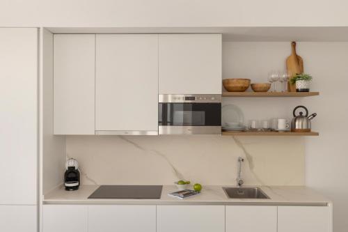 a kitchen with white cabinets and a microwave at Candelaria10 in Cádiz