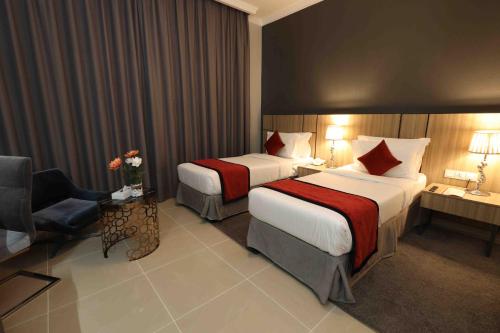 a hotel room with two beds and a chair at Fortis Hotel Fujairah in Fujairah