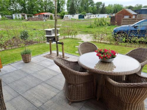 a table with chairs and a bowl of flowers on a patio at Nieuw - Luxe Blokhut Chalet in bosrijke omgeving in Anloo