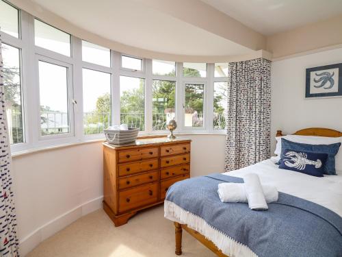1 dormitorio con 1 cama, vestidor de madera y ventanas en Nairn, en Braunton