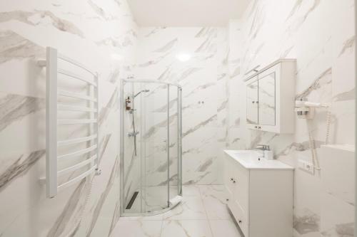 bagno bianco con doccia e lavandino di GRAND CROWN a Vilnius