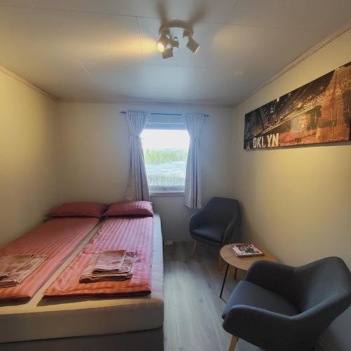 a bedroom with a bed and two chairs and a window at Glomma House in Kongsvinger