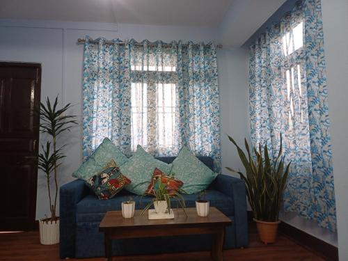 een woonkamer met een blauwe bank met kussens bij Bluebird'snest in Gangtok