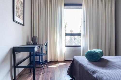 a bedroom with a bed and a desk and a window at King David Apartment - J&J in Jerusalem