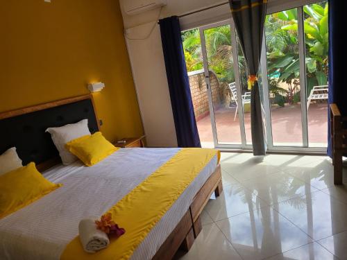 Hotel Les Cygnes في أنتاناناريفو: غرفة نوم بها سرير وبجدران صفراء ونافذة كبيرة