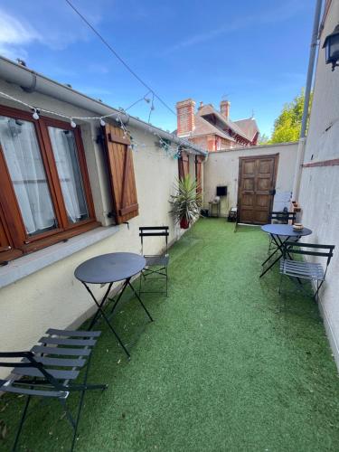 zwei Tische und Stühle auf einer Terrasse mit Gras in der Unterkunft Le duo des Garennes - Entre confort & indépendance - Cour extérieure en centre ville de Blois in Blois