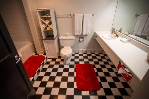 a bathroom with a white toilet and a checkerboard floor at Nuk's Executive Suites in De Pere