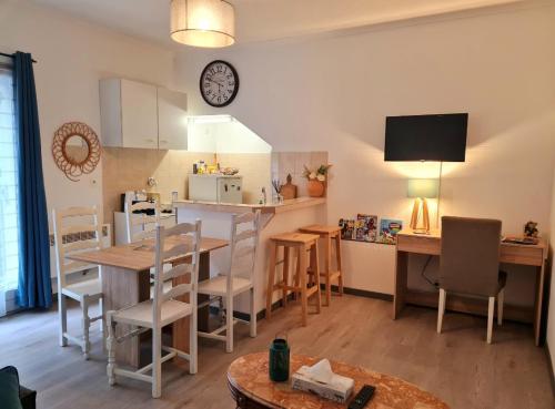 eine Küche und ein Wohnzimmer mit einem Tisch und einer Uhr an der Wand in der Unterkunft Les alouettes in Nanterre