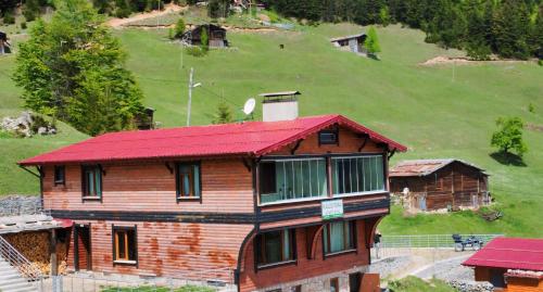 a wooden house with a red roof on a hill at Kalispera Apart Otel in Uzungol