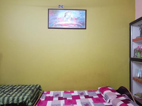 Pokój z telewizorem na ścianie i łóżkiem w obiekcie Sangeeta's w mieście Ayodhya