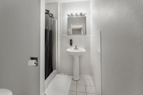 a white bathroom with a sink and a mirror at Mia's Boutique Hotel in Nags Head