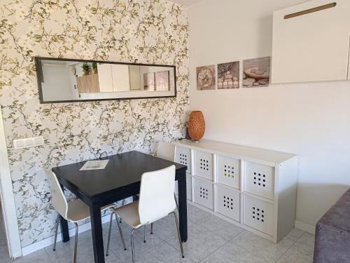 comedor con mesa negra y sillas blancas en Precioso Dúplex con terraza a 5 minutos playa y 20 minutos de Barcelona, en Premiá de Mar