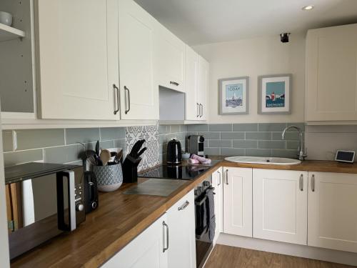 a white kitchen with white cabinets and a sink at Ferry View - Views over the Dart, elegant three storey house, unique Sky Room in Dartmouth